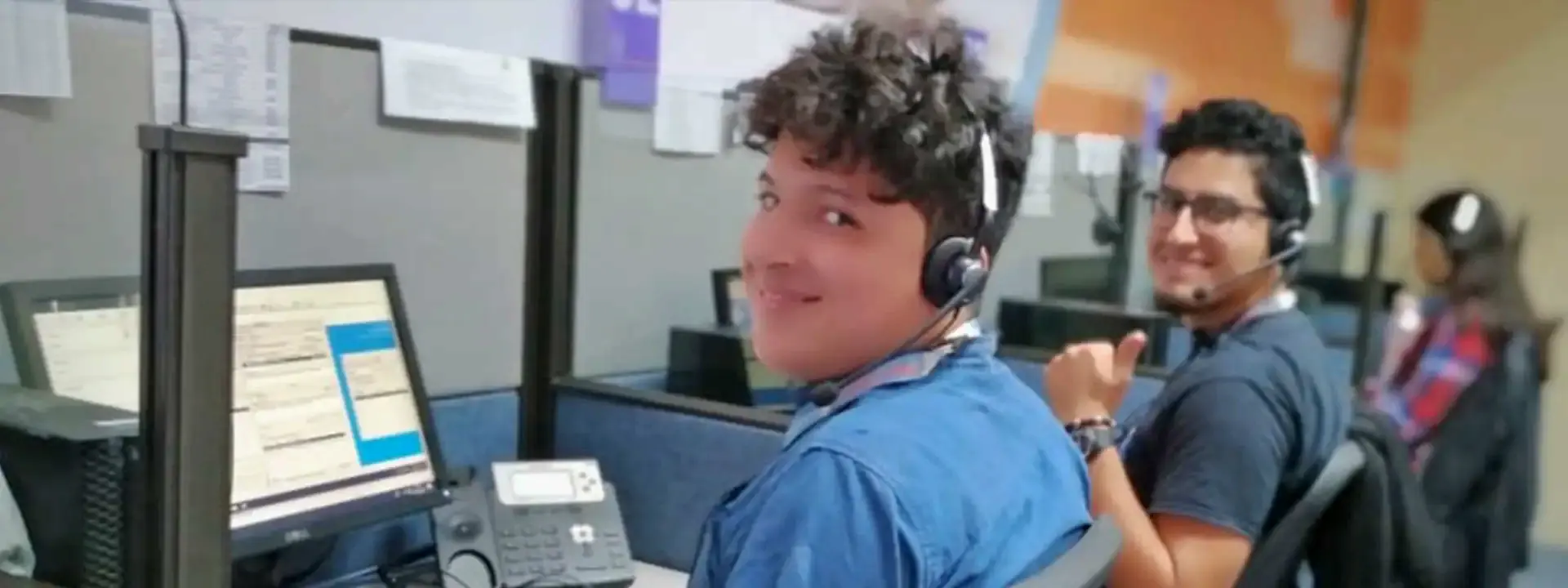 Two agents smiling at their desks